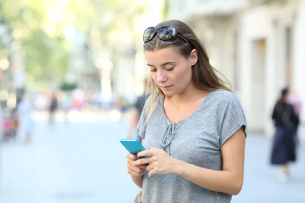 Poważny nastolatek tekstylny na telefon stojący na ulicy — Zdjęcie stockowe