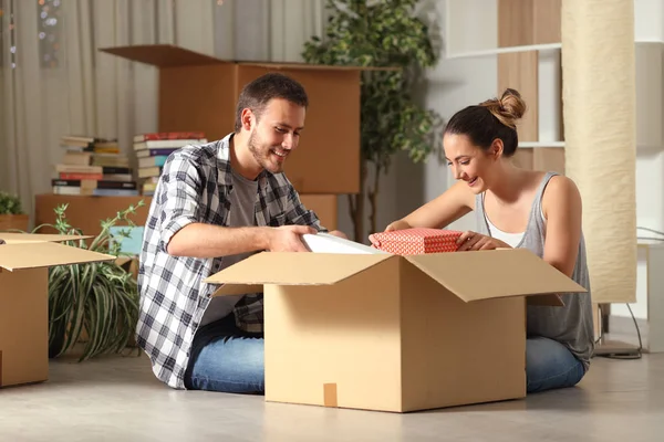 Feliz pareja unboxing pertenencias moviendo casa en el suelo — Foto de Stock