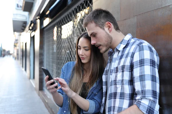 Seriöses Paar nutzt Smartphone auf der Straße — Stockfoto