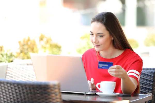 Seriös tjej betalar online med en bärbar dator och kreditkort i en bar — Stockfoto