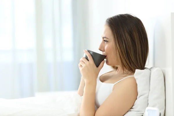 Perfil de una mujer tomando café en la cama — Foto de Stock