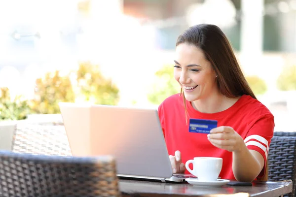 Счастливый подросток оплачивает онлайн с помощью ноутбука и кредитной карты — стоковое фото