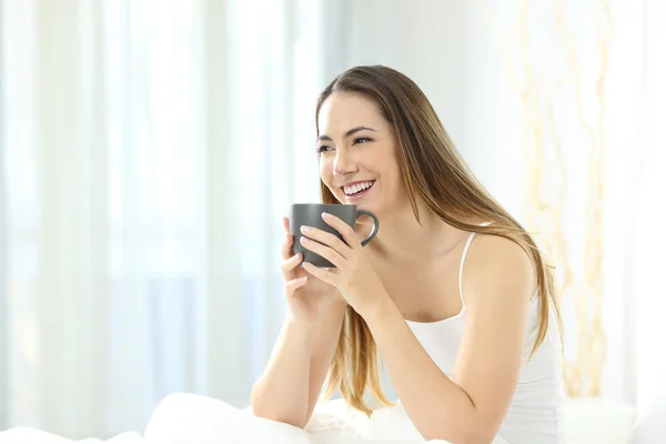 Счастливая женщина пьет кофе на кровати утром — стоковое фото