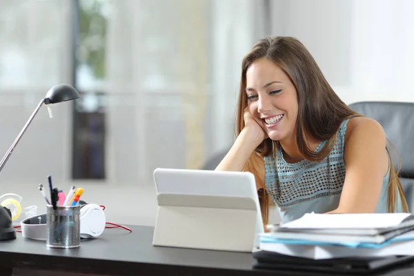Glückliche Frau, die Tablet-Medien zu Hause auf dem Schreibtisch betrachtet — Stockfoto