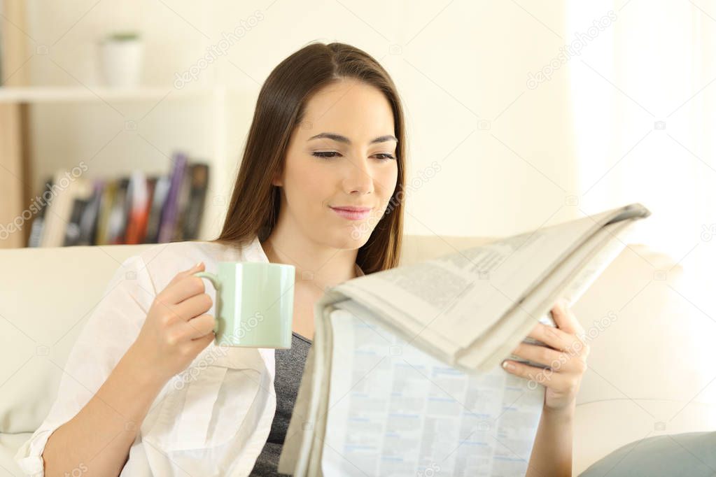 Woman at home reading a newspaper drinking coffee