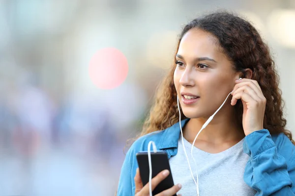 Blandad ras kvinna sätta hörlurar lyssnar på musik — Stockfoto