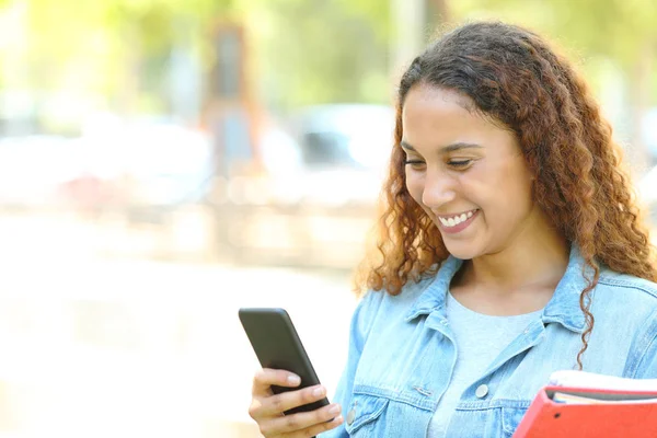 Gelukkige gemengde race student het controleren van de telefoon in een park — Stockfoto