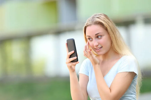Teen using smart phone as a mirror outdoors — Stock Photo, Image