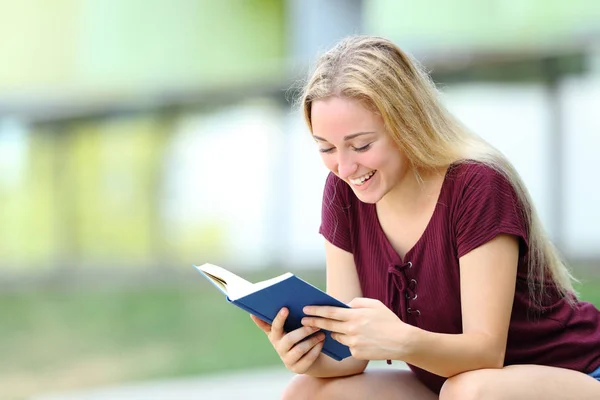 Gelukkige student studeren een boek buitenshuis lezen — Stockfoto