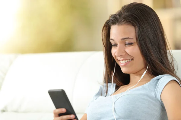 Lycklig tjej lyssnar på musik bär öronsnäckor hemma — Stockfoto