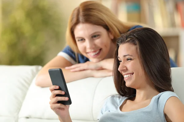 Счастливые друзья смотрят содержимое смартфона дома — стоковое фото
