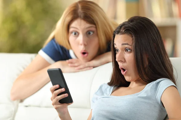 Amazed friends checking phone online news at home — Stock Photo, Image