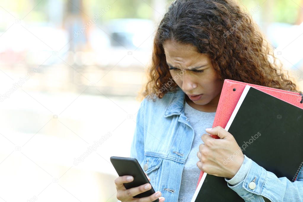 Sad mixed race student checking phone messages