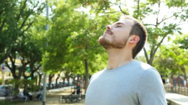 Smiley rahat adam bir parkta ayakta derinden temiz hava nefes
