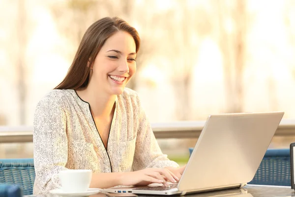 Mujer está usando un ordenador portátil en una cafetería al atardecer — Foto de Stock