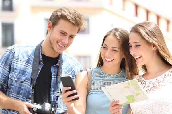 Счастливые туристы путешествуют проверяя телефон и карту — стоковое фото