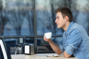 Kahve dükkanındaki pencereden bakan ciddi bir adam.