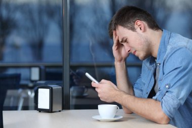 Üzgün adam bir kafede telefon mesajı kontrol