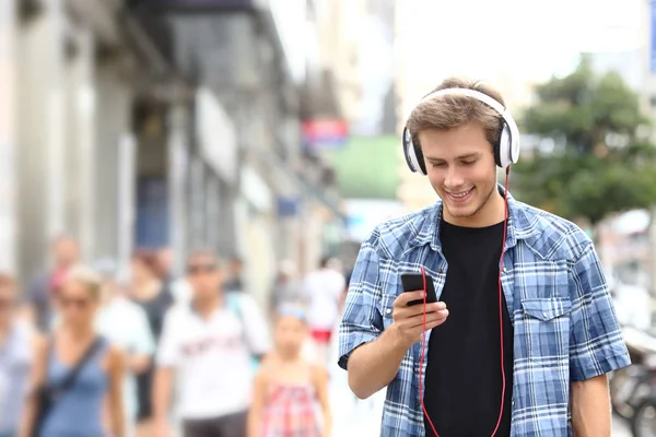 Menino feliz andando ouvindo música na rua — Fotografia de Stock