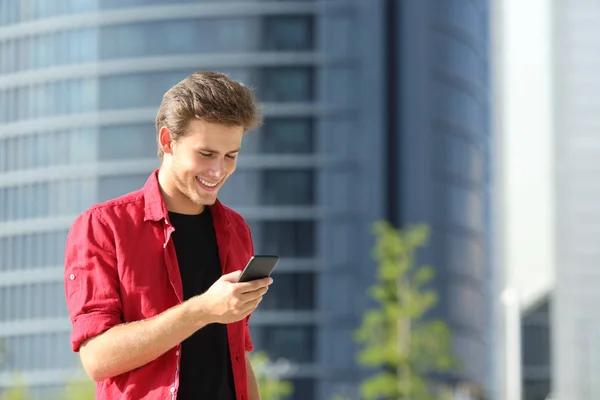 Hombre feliz usando un teléfono inteligente caminando por la calle — Foto de Stock