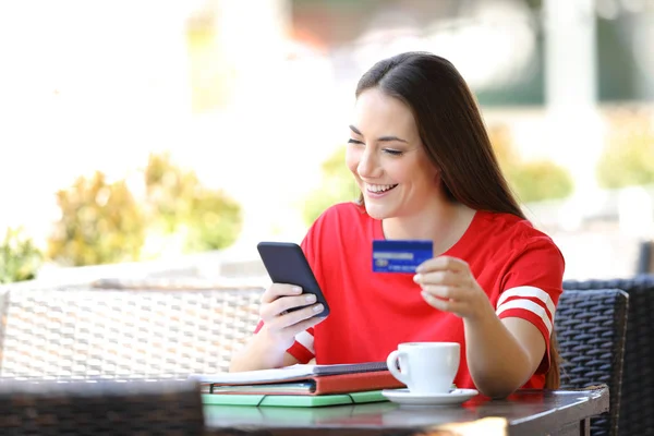 Estudante feliz em vermelho pagando online com cartão de crédito — Fotografia de Stock