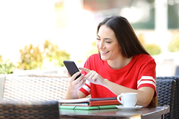 Happy student in red browsing phone content in a bar — Stock Photo, Image