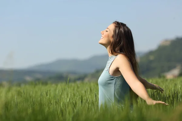 Mulher feliz respirando ar fresco e tocando trigo — Fotografia de Stock