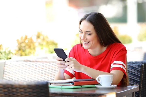 Happy student in red texting on smart phone in a bar — Stock Photo, Image