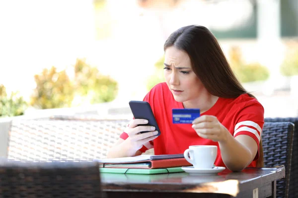 Estudiante preocupado pagando en línea con tarjeta de crédito en un bar — Foto de Stock