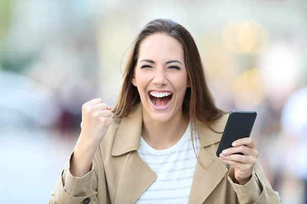 Mujer emocionada sosteniendo el teléfono mirando a la cámara —  Fotos de Stock