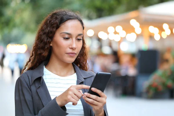 Vážná smíšená závodní žena používající telefon na ulici — Stock fotografie