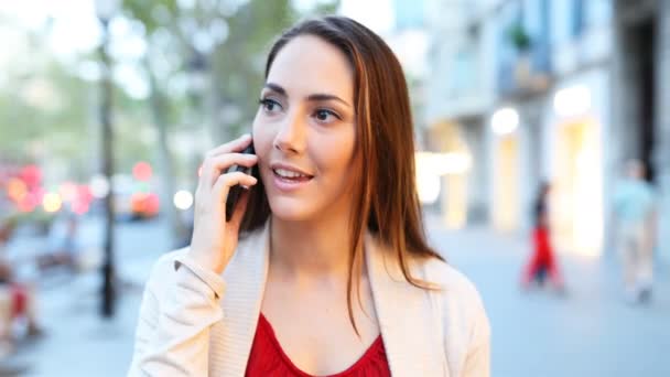 夕方に通りを歩くスマートフォンで話す女性の正面図 — ストック動画