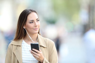 Telefonda müzik dinleyerek yürüyen pensive kadın