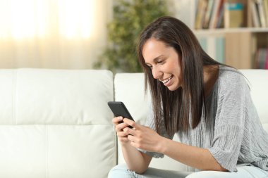 Evde akıllı telefon kullanan mutlu kadın