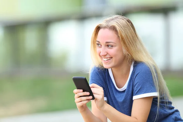 Gelukkig tiener meisje houdt telefoon kijken naar kant — Stockfoto