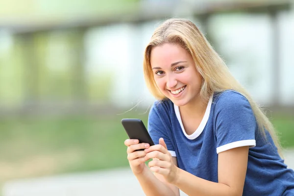 Tonårs flicka tittar på kamera håller smart telefon — Stockfoto
