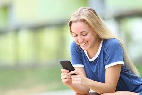 Happy teenage girl texing message on smarphone — стоковое фото