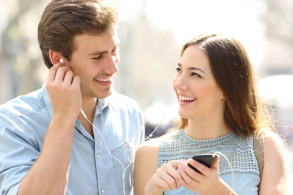 Pareja caminando escuchando música compartiendo auriculares — Foto de Stock