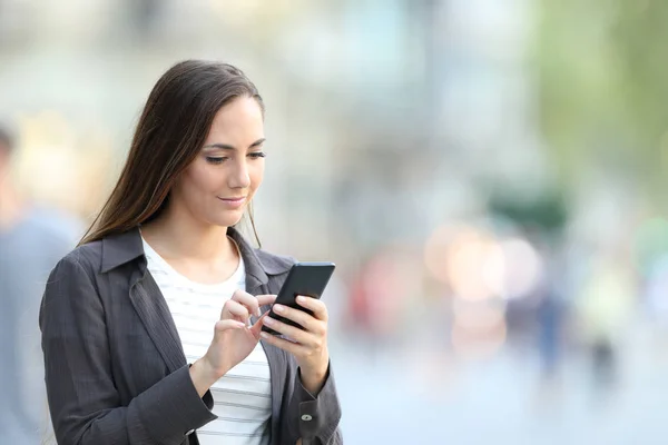 Sério feminino navegação conteúdo do telefone na rua — Fotografia de Stock