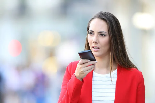 Mujer seria en rojo usando reconocimiento de voz en el teléfono —  Fotos de Stock