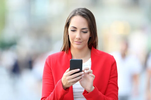 Framsidan av allvarliga kvinnan i rött med hjälp av telefon — Stockfoto