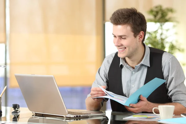 Happy worker comparing laptop content and documents — Stock Photo, Image