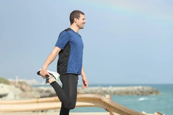 Runner stretching benen kijken naar zee op het strand — Stockfoto