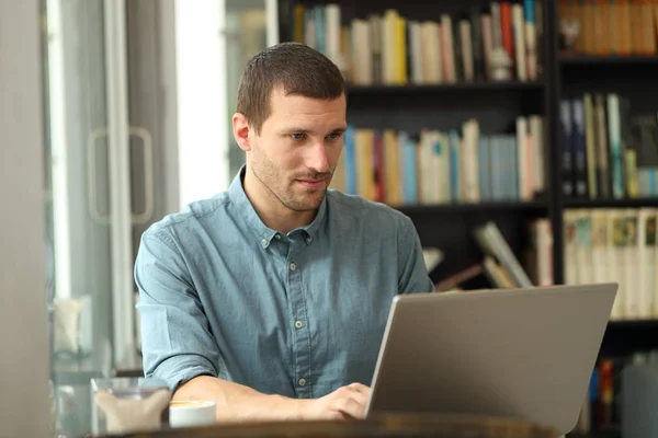 Uomo adulto serio che scrive sul computer portatile in una caffetteria — Foto Stock