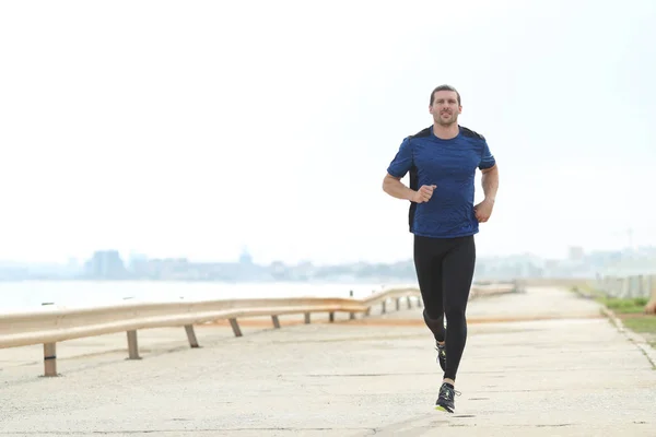 Vue de face du coureur qui court sur la plage — Photo