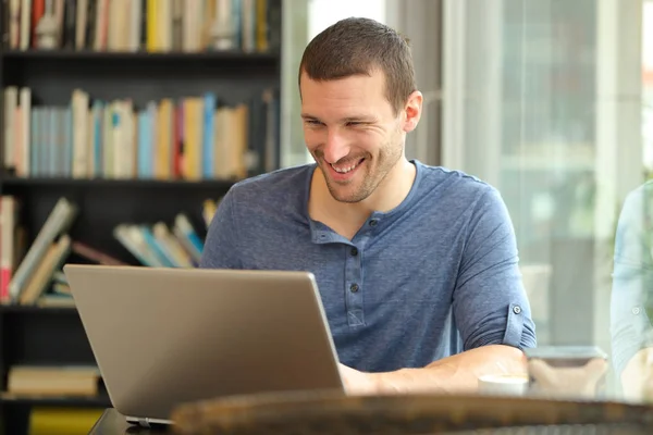 Homem feliz usando um laptop sentado em uma cafeteria ou em casa — Fotografia de Stock