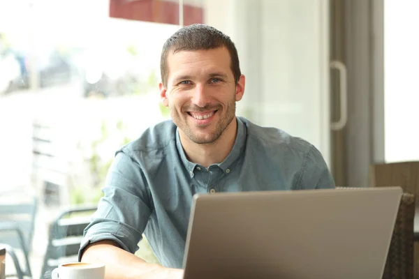 Щасливий чоловік з ноутбуком позує в кав'ярні — стокове фото