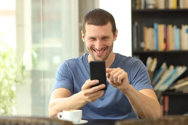 Framsidan av en lycklig man med telefon i en bar — Stockfoto