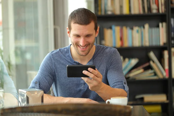 Homem feliz assistindo mídia no telefone inteligente em um bar — Fotografia de Stock