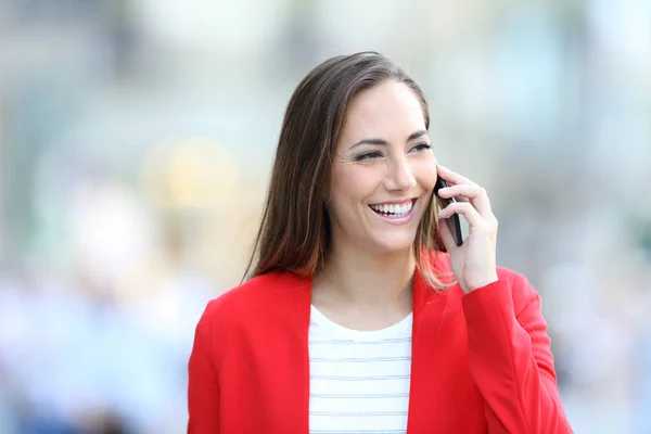 Happy woman in red talking on phone in the street — Stock Photo, Image